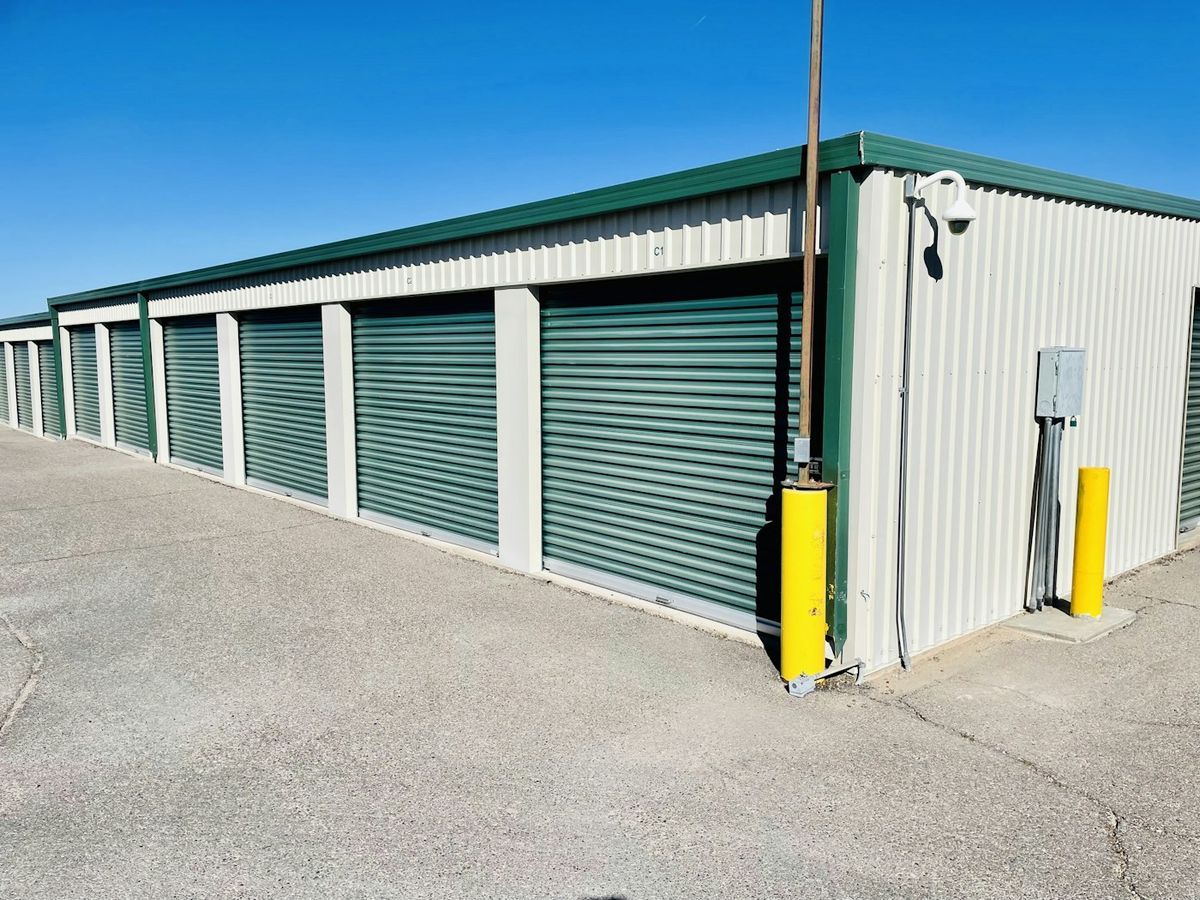 Exterior row of closed self-storage units with roll-up doors under a clear sky