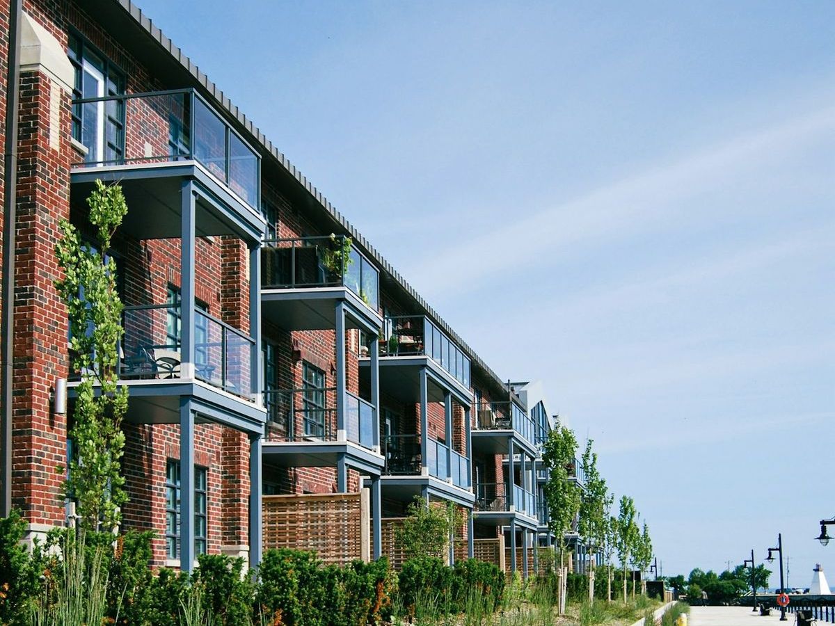 Modern brick multifamily apartment building with balconies along a landscaped street